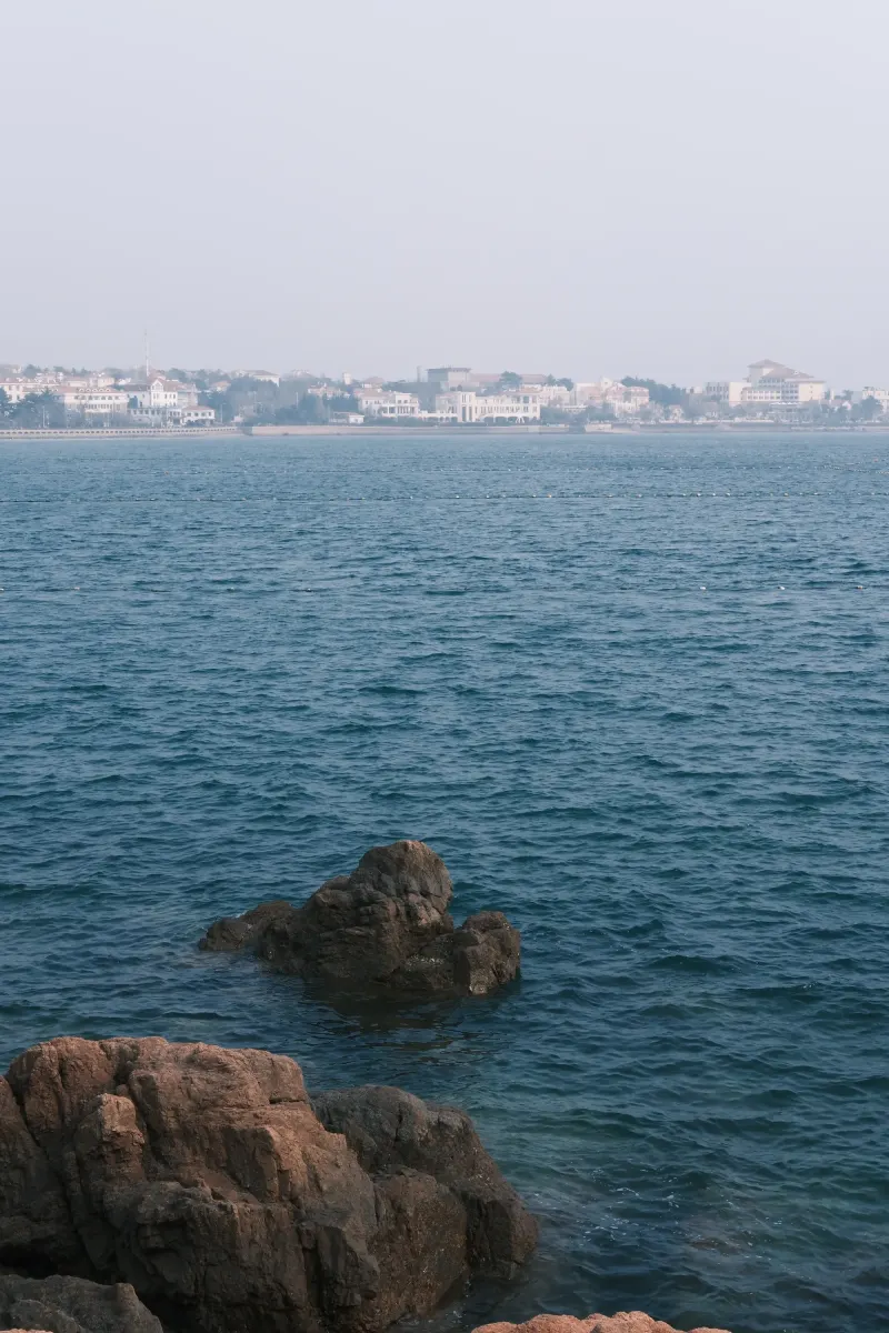 海边礁石、蓝色海面与远处建筑