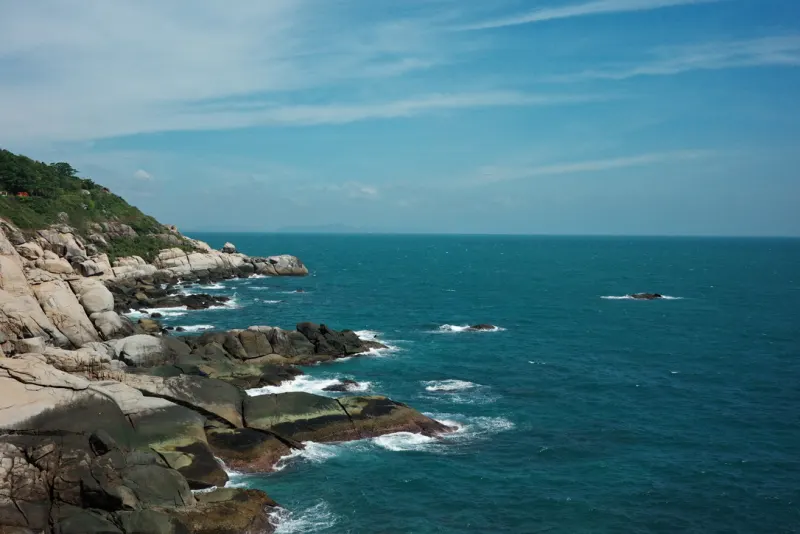 阳光下延伸入蓝色海面的岩岸